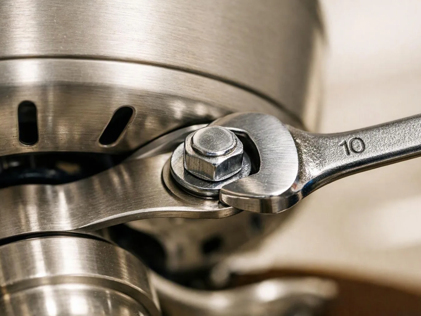 A close-up shows a wrench tightening a nut on a brushed metal machine component